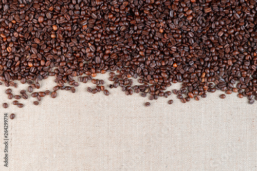 Roasted coffee beans on linea canvas with space on the bottom.