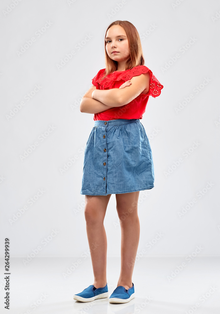 childhood and people concept - displeased girl in red shirt with crossed arms over grey background childhood and people concept - displeased girl in red shirt with crossed arms over grey background