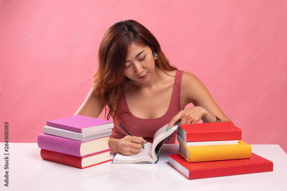 Young Asian woman read a book with books on table. Young Asian woman read a book with books on table.