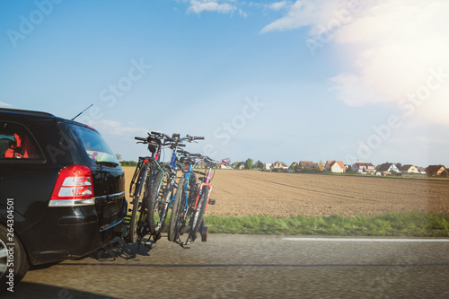 View from the highway over the plowed land and fast Opel car carrying four bikes   photo