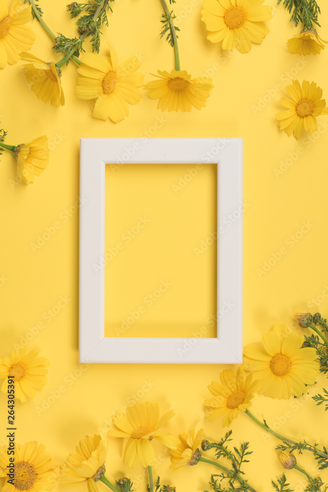 Obraz premium Flowers composition. Chamomile flowers with photo frame on yellow background. Spring, summer concept. Flat lay, top view, copy space
