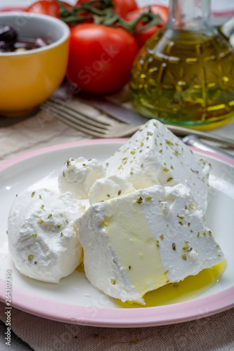 Fresh young soft white Feta cheese with olive oil on plate seasoned with dried oregano herb