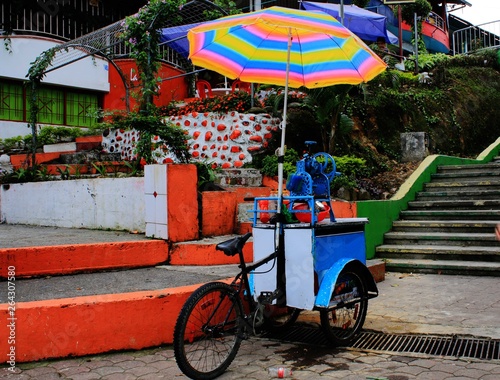 Local small shop on a bike selling drink under a bright and colorful umbrella in south america photo