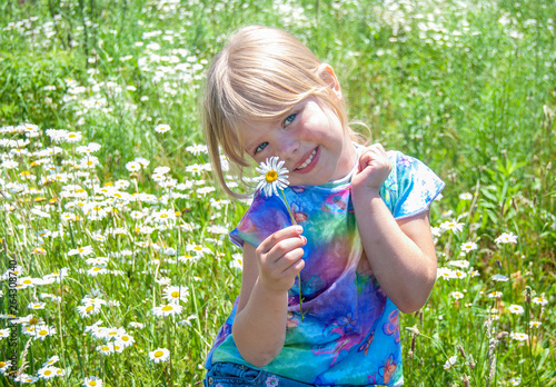 smiling blond Caucasian young girl in wild daisy meadow