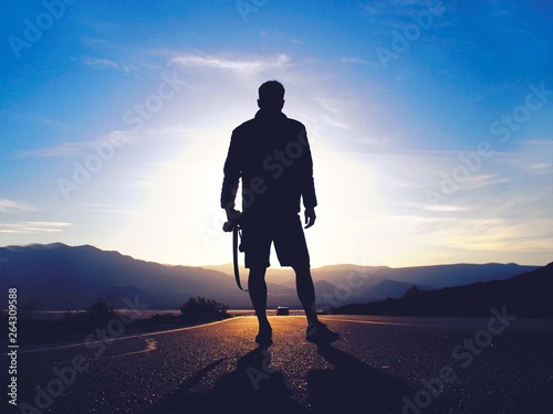 silhouette of man on road at sunset