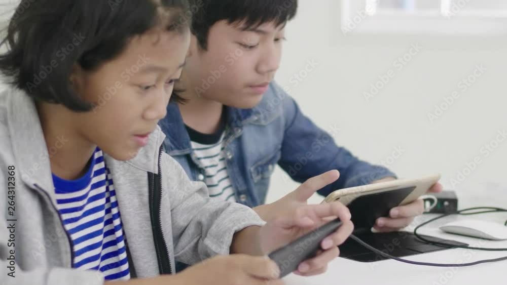 Close up of asian cute girl and young boy playing in competitive video game on smartphones and tablet, Holding them in horizontal landscape mode. 60fps in dolly Shot. Close up of asian cute girl and young boy playing in competitive video game on smartphones and tablet, Holding them in horizontal landscape mode. 60fps in dolly Shot.