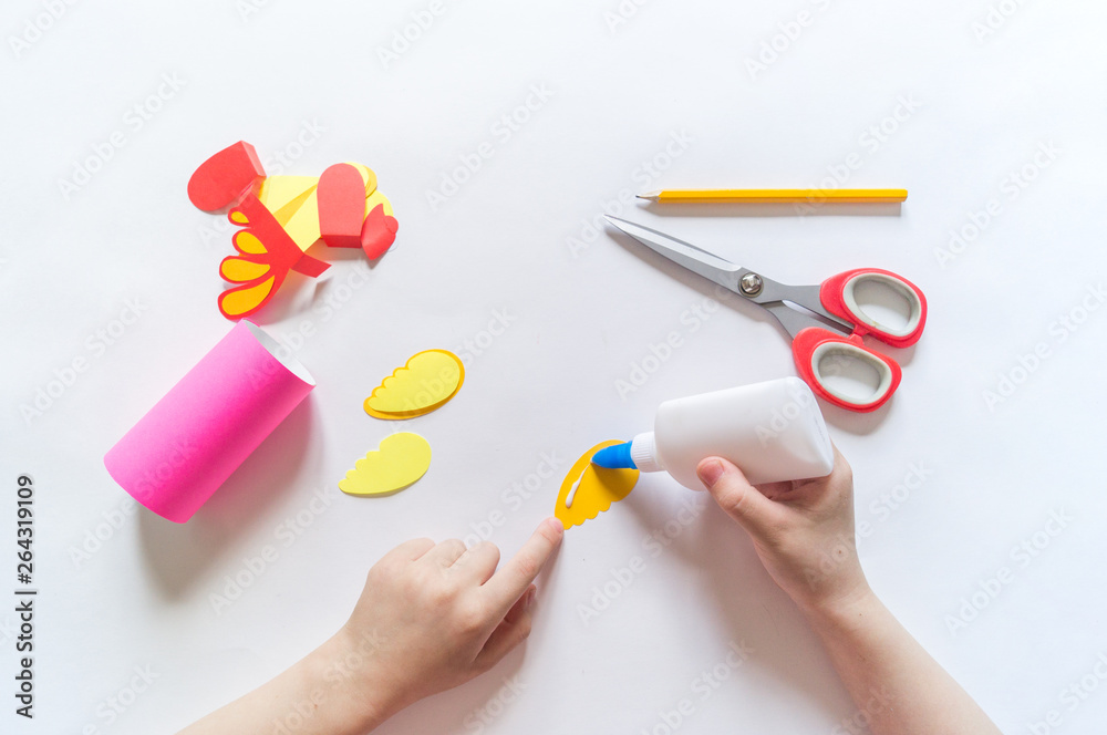 The child makes a craft from cardboard. Paper parrot pink. Hands girls. The child makes a craft from cardboard. Paper parrot pink. Hands girls.