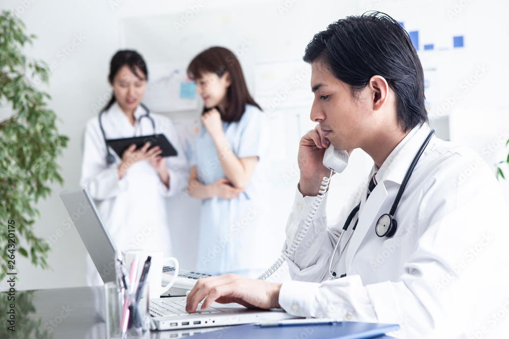 Fototapeta premium 若手男性医師が同僚と電話で話している