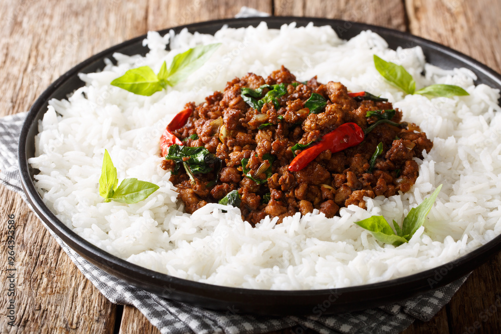 Stir fry basil chicken with chili pepper and soy sauce with a side dish of rice close-up on a plate. horizontal Stir fry basil chicken with chili pepper and soy sauce with a side dish of rice close-up on a plate. horizontal