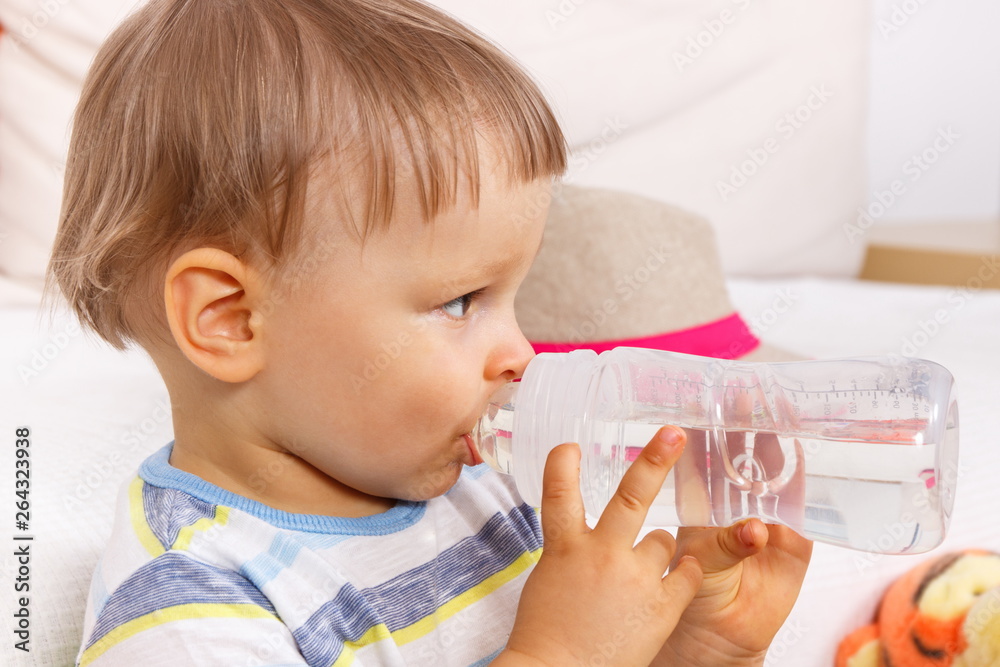 Thirsty little preschooler drinking water from bottle