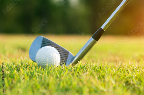 Golf clubs and golf balls on a green lawn in a beautiful golf course