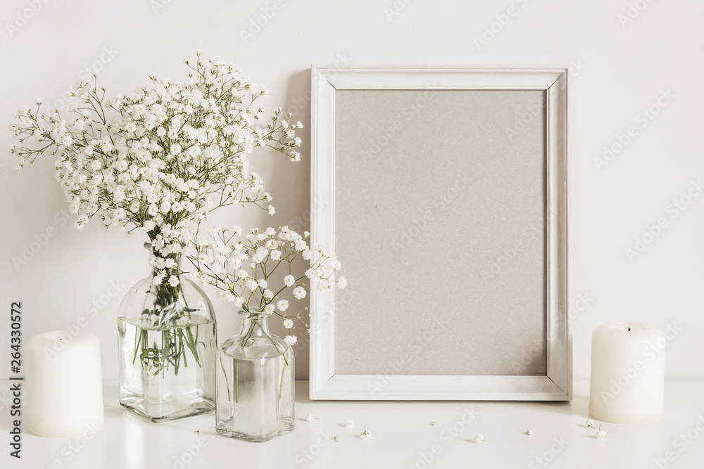 Candles, gypsophila flowers and photo frame on table wall background. Front view mockup