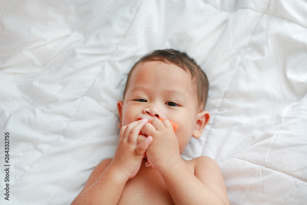 Adorable baby boy lying on bed with bite soft rubber toy. Close-up shot. Adorable baby boy lying on bed with bite soft rubber toy. Close-up shot.