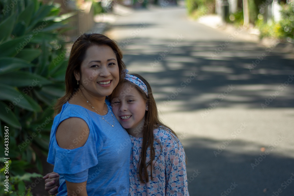 Latina Mother and Daughter Smiling and laughing on suburban street Latina Mother and Daughter Smiling and laughing on suburban street