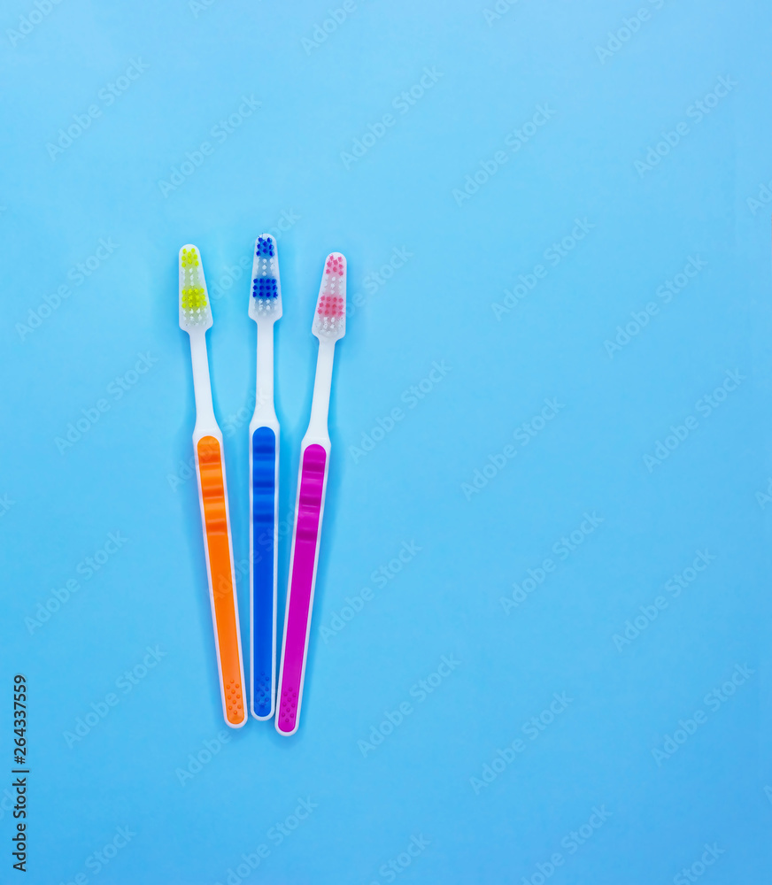 Multi-colored toothbrushes on a blue background with copy space. Flat lay. Top view. Multi-colored toothbrushes on a blue background with copy space. Flat lay. Top view.