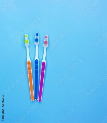 Multi-colored toothbrushes on a blue background with copy space. Flat lay. Top view.