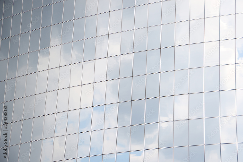 Reflection of a cloudy sky in glass wall of an office building. Multi-storey glass office building. Reflection of a cloudy sky in glass wall of an office building. Multi-storey glass office building.