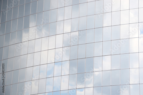 Reflection of a cloudy sky in glass wall of an office building. Multi-storey glass office building.