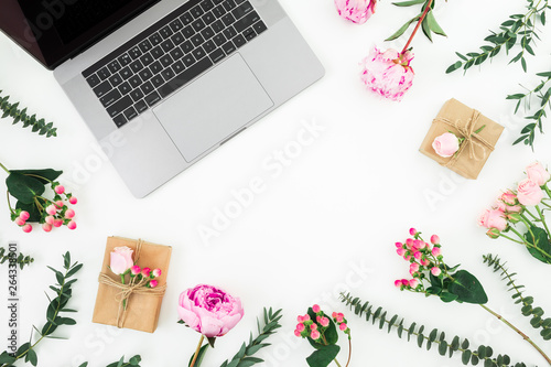 Office workspace with laptop and pink flowers on white background. Top view. Flat lay.