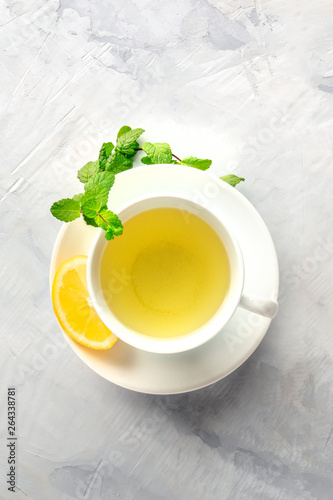 A photo of a cup of tea with lemon and mint leaves, shot from above with copy space
