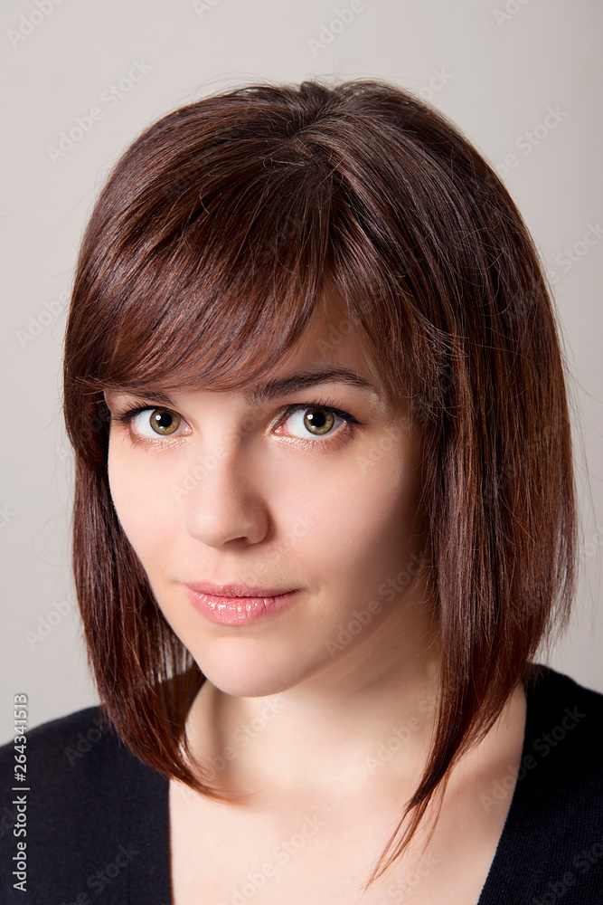 Closeup portrait of brown-haired girl with hairstyle and clean skin on a white background. Closeup portrait of brown-haired girl with hairstyle and clean skin on a white background.