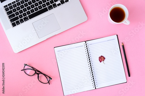 Office desk table with notebook,smartphone and coffee cup laptop. pink background flat lay top view