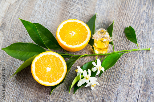 Juicy Orange cut in two parts and neroli, flowers of orange tree, on rustic wood background. The Orange blossom is the fragrant flower of the Citrus is used in perfume and tea, aphrodisiac.