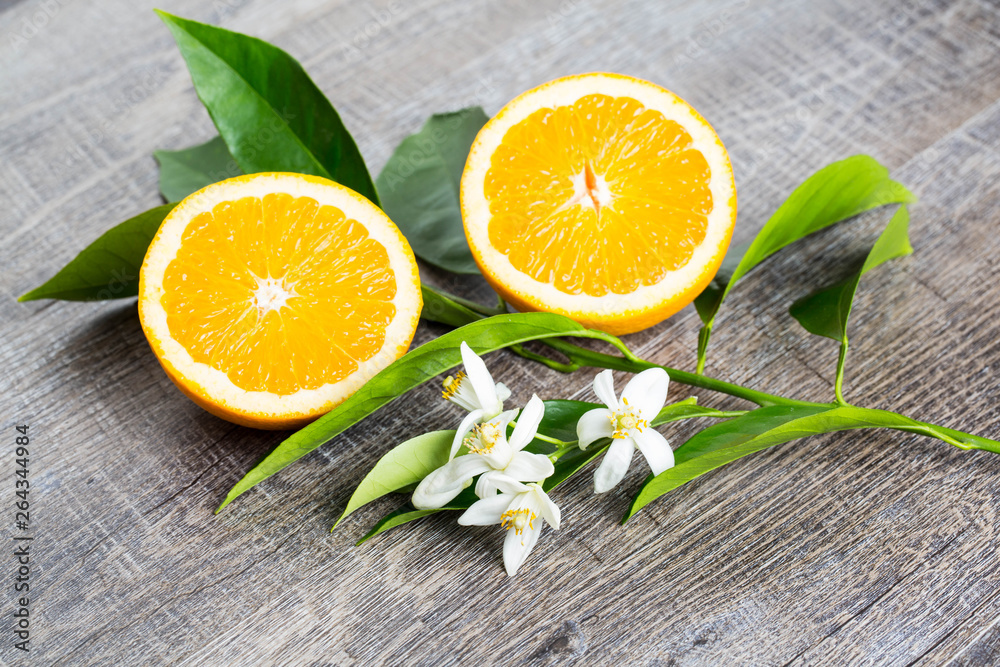 Juicy Orange cut in two parts and neroli, flowers of orange tree, on rustic wood background. The Orange blossom is the fragrant flower of the Citrus is used in perfume and tea, aphrodisiac. Juicy Orange cut in two parts and neroli, flowers of orange tree, on rustic wood background. The Orange blossom is the fragrant flower of the Citrus is used in perfume and tea, aphrodisiac.
