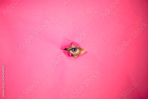 The eye looks through the hole in pink paper