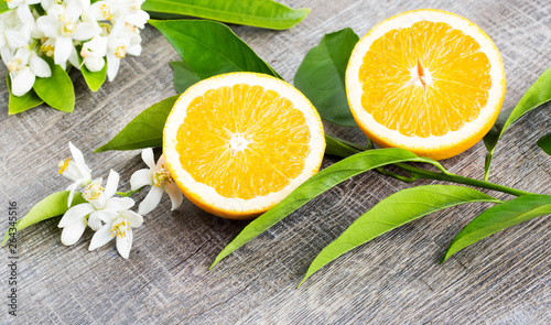 Juicy Orange cut in two parts and neroli, flowers of orange tree, on rustic wood background. The Orange blossom is the fragrant flower of the Citrus is used in perfume and tea, aphrodisiac.