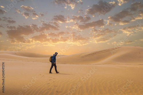A man travel in the desert by walking . 