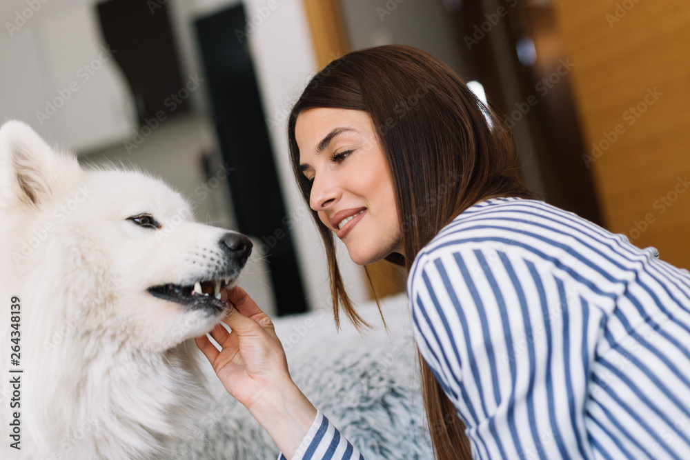 Cute girl petting her dog. Beautiful girl having fun with her dog and enjoying herself. Girl and her dog at home