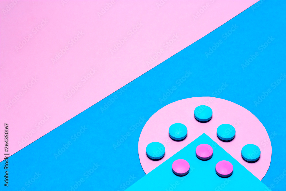 blue and pink tablets laid out in the form of an arrow on a paper background of blue and pink with copy space blue and pink tablets laid out in the form of an arrow on a paper background of blue and pink with copy space