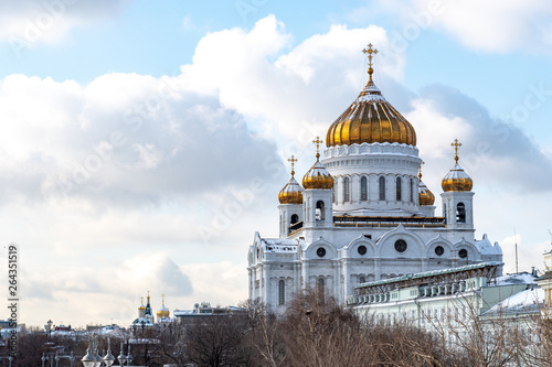 winter view of the snow-covered Golden domes of the Cathedral of Christ the Saviour with white walls against the cloudy sky