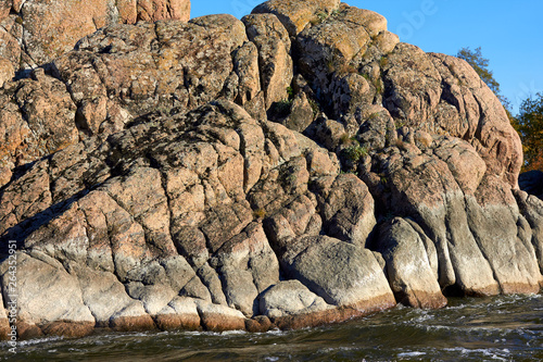 Сliffs on the banks of the mountain river with rapids flowing along rocky banks in wilderness at autumn. Waves, spray, foam and crag.