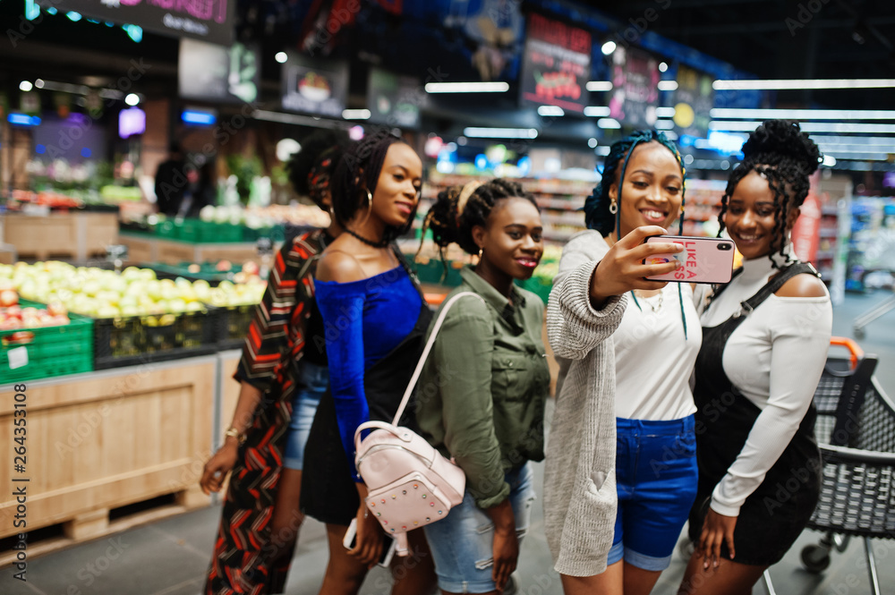 Group of five african womans making selfie by phone at supermarket.