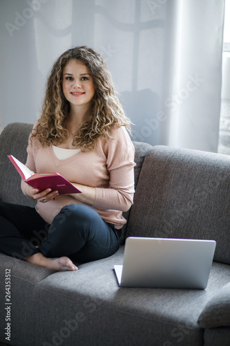A pregnant woman working on a laptop. Pregnant typing something on laptop while sitting at her workplace in office.