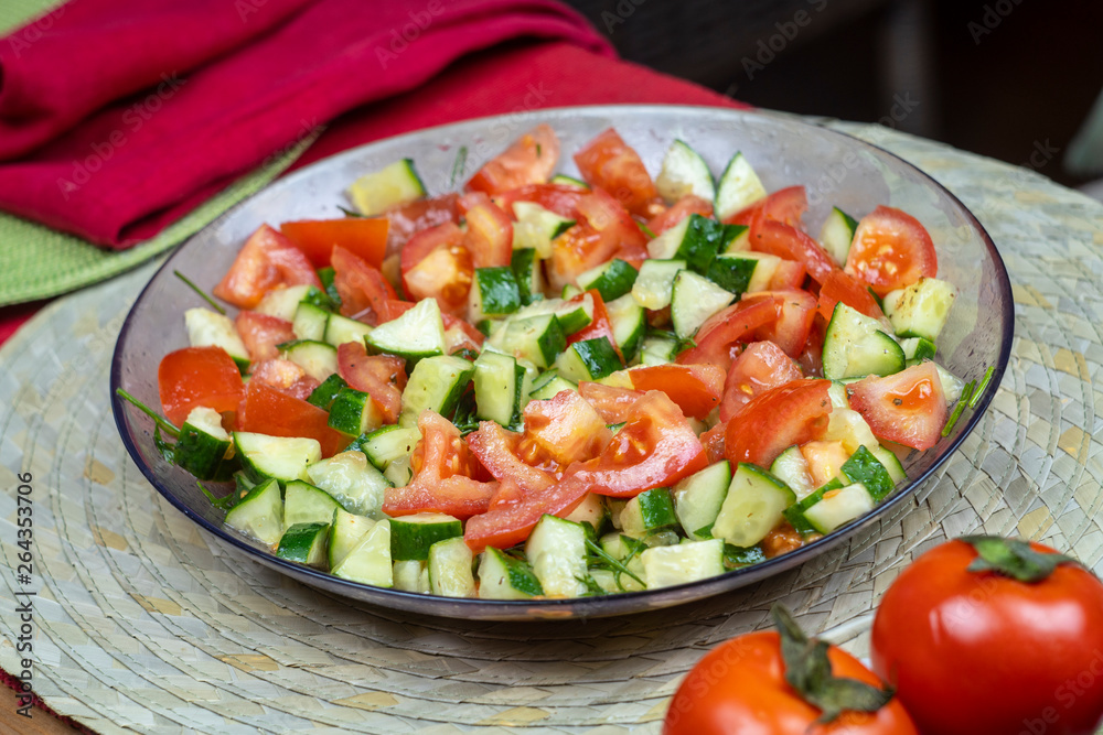 Delicious natural salad of fresh vegetables tomatoes and cucumbers with herbs, healthy food, cooking, close-up
