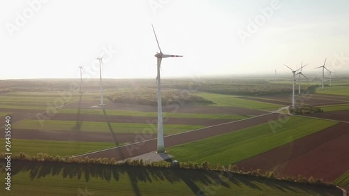 Windmills on agricultural area at countryside - Scenic drone shot at sunset of renewable energy photo