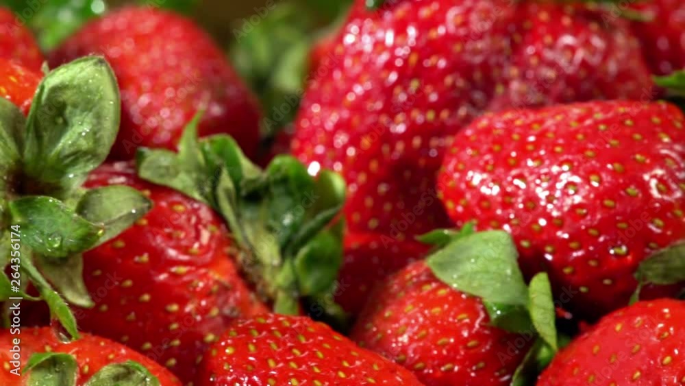 Strawberry on wooden table, bedabbled with dew and leaved. Harvesting pile of picked freshly red berry and green leaves close up with horizontal motion . Strawberry on wooden table, bedabbled with dew and leaved. Harvesting pile of picked freshly red berry and green leaves close up with horizontal motion .