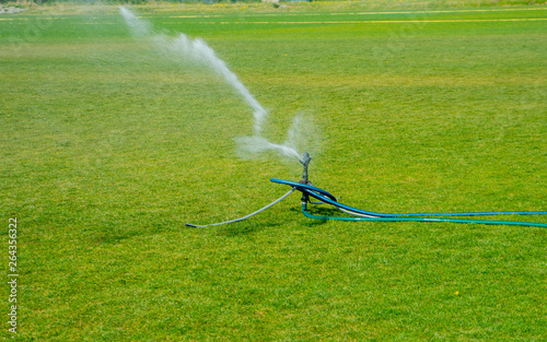 Irrigation turf. Sprinkler watering football field. System working on fresh green grass on football or soccer stadium photo