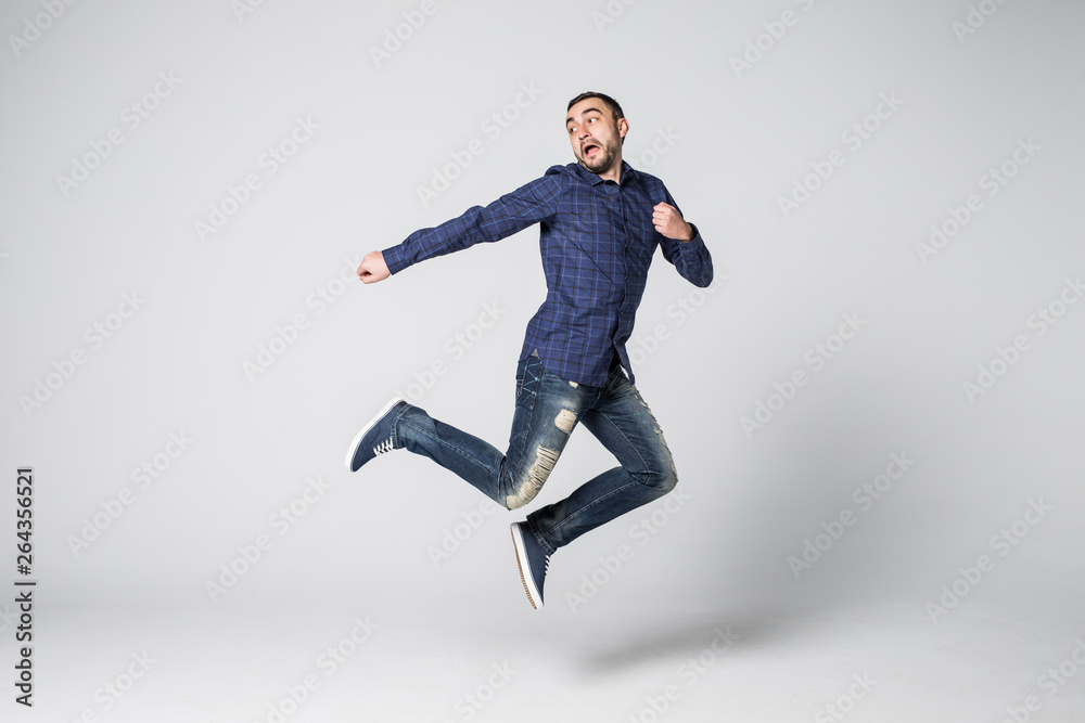 Full length portrait of a happy excited bearded man jumping and looking at camera isolated over white background