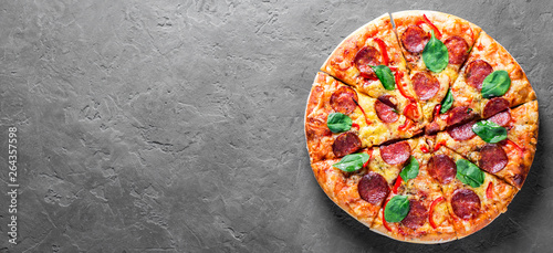 Pepperoni Pizza with Mozzarella cheese, salami, pepper, Spices and Fresh spinach. Italian pizza on Dark grey black slate background. with copy space. top view