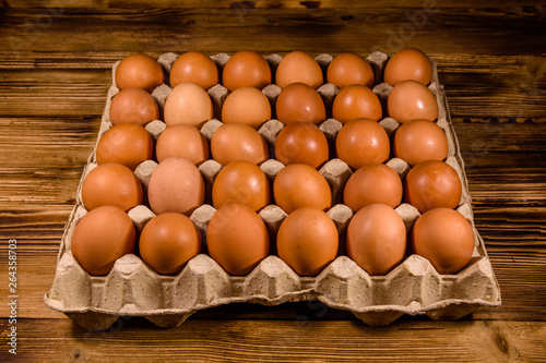 Pile of the hen eggs in paper tray on wooden table