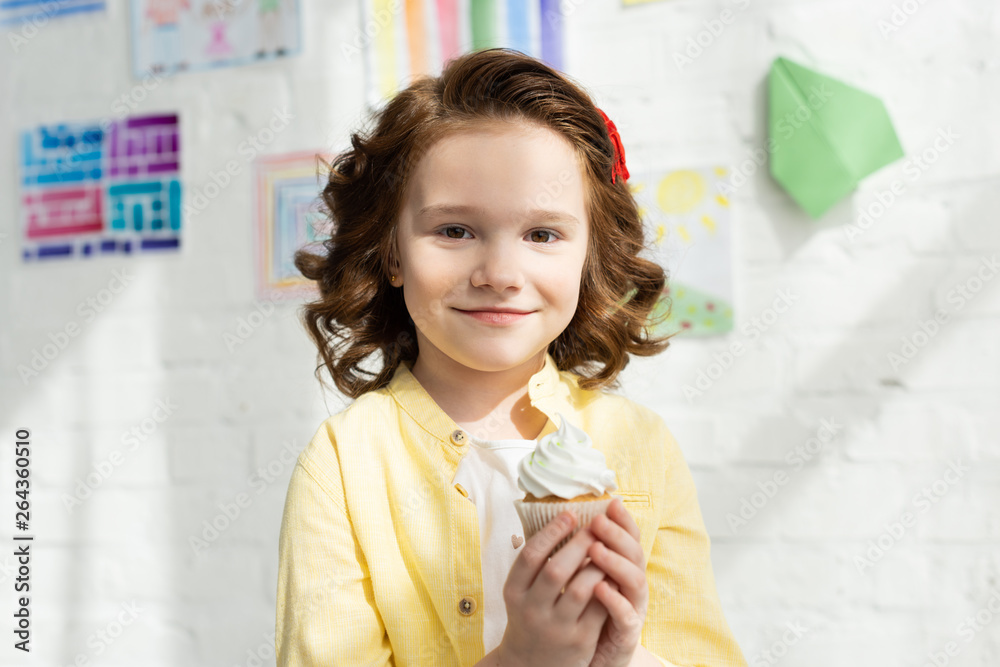 adorable kid holding delicious cupcake and looking at camera at home adorable kid holding delicious cupcake and looking at camera at home