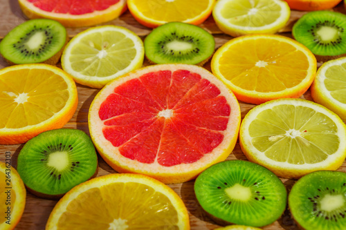 frame with slices of oranges, lemons, kiwi, grapefruit pattern on wooden background. Copy space