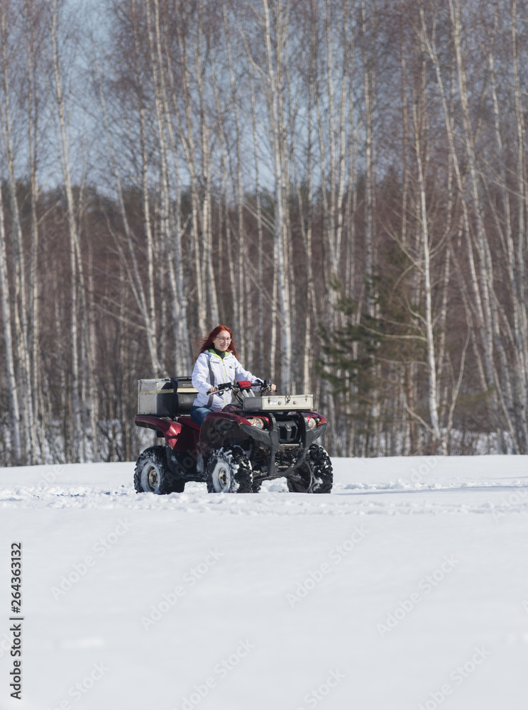 A winter forest. A woman with ginger hair riding snowmobile A winter forest. A woman with ginger hair riding snowmobile