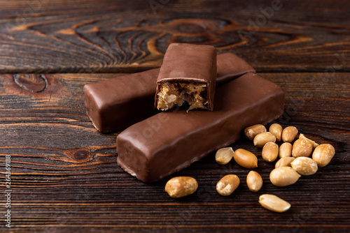 Chocolate bar with caramel and peanut on dark wooden background. 