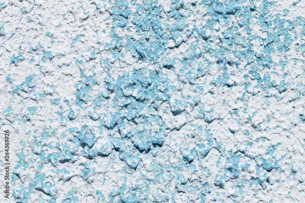 blue concrete wall with bulks of cement in bulk, with cracked white paint, close-up