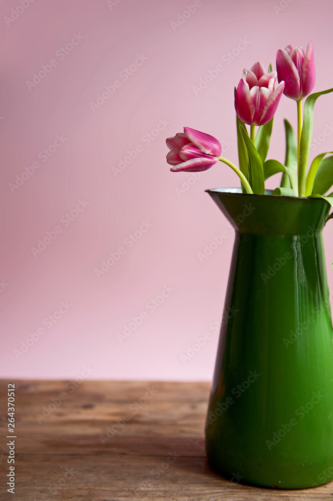 Pink tuplis flowers in green vase on the pink background